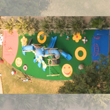 Green EPDM playground flooring with colorful smiley faces flowers and circular designs